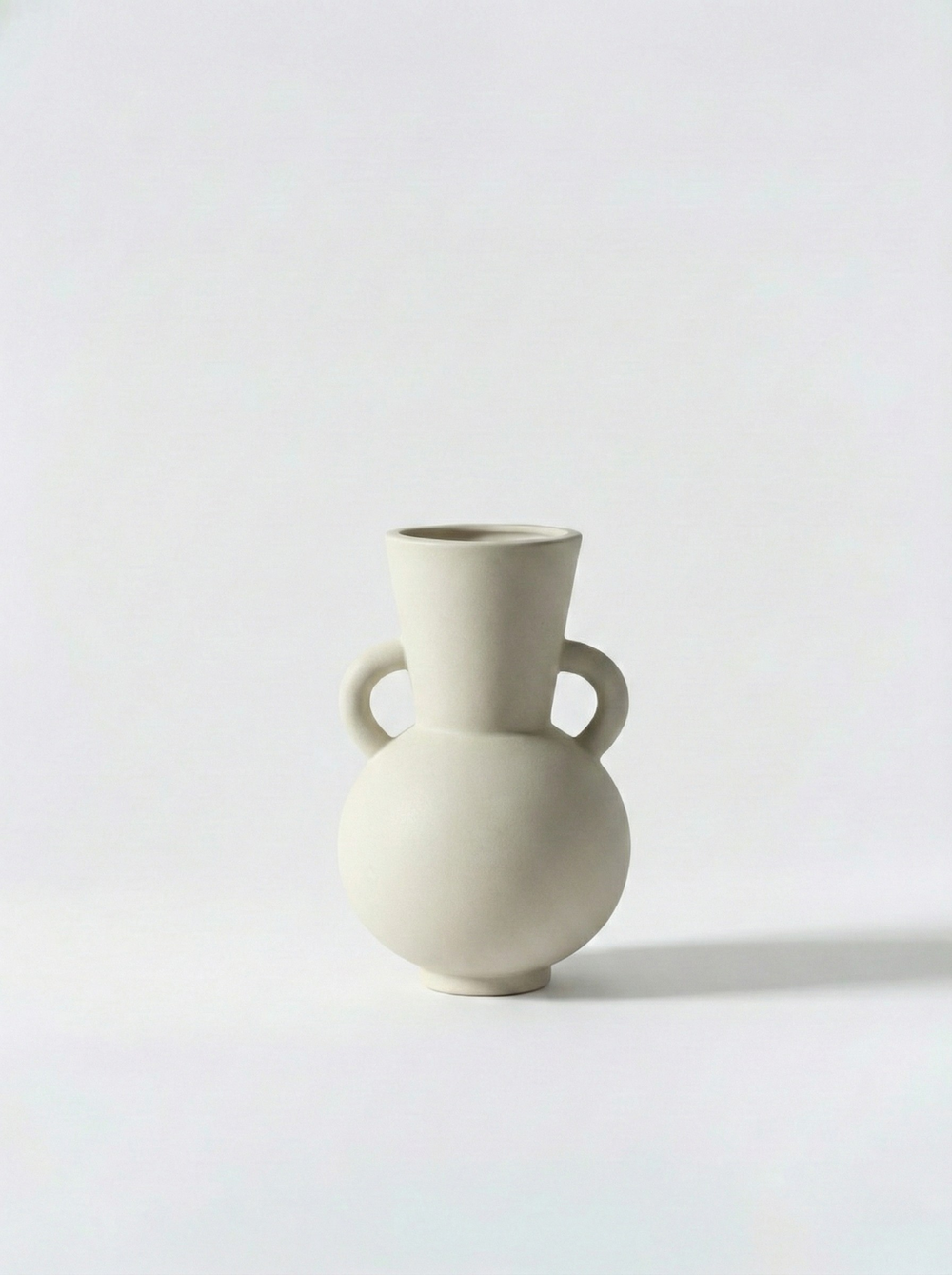 Minimalist white ceramic vase with two handles on a light grey background