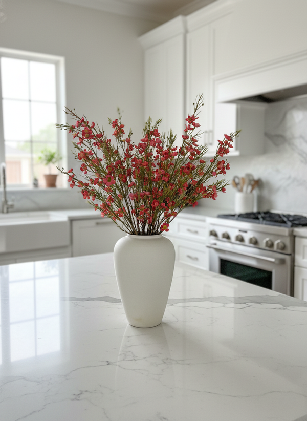 Realistic real-touch red faux wax flowers arranged in a matte white ceramic vase on a bright modern kitchen #red