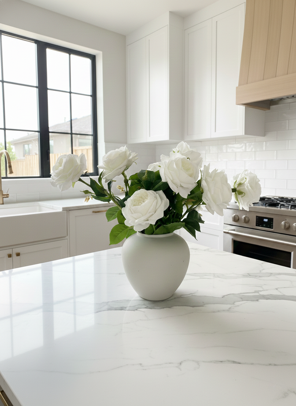 Artificial white rose arrangement in a matte ceramic vase styled on a marble kitchen island in a modern white kitchen #white