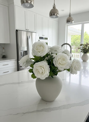 Premium white faux ranunculus arrangement in a matte white ceramic vase styled on a bright modern kitchen bench top #white 