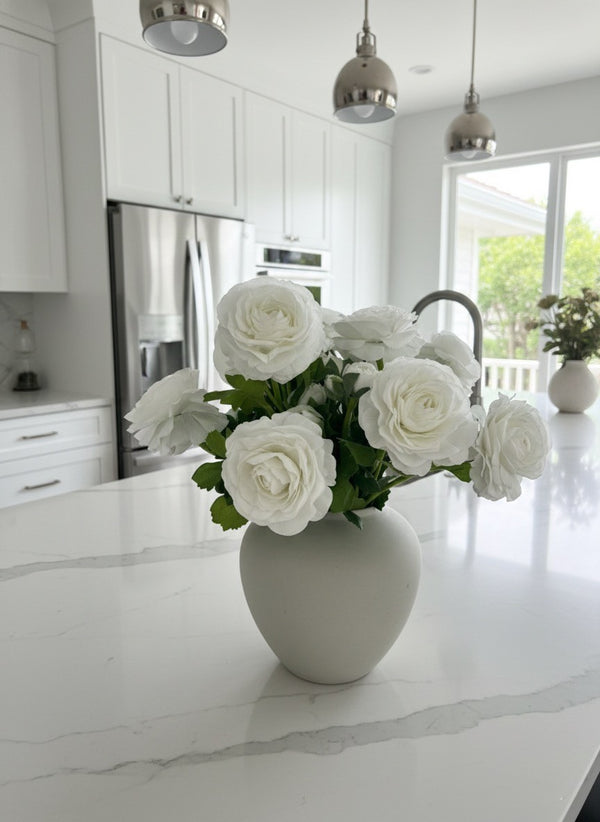 Premium white faux ranunculus arrangement in a matte white ceramic vase styled on a bright modern kitchen bench top #white 