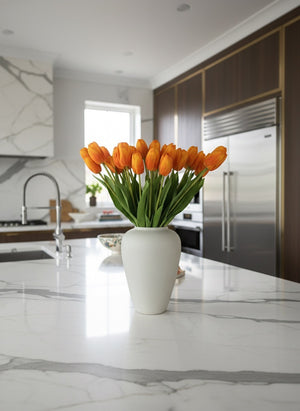 Realistic orange faux tulips arranged in a minimalist ceramic vase styled on a modern marble kitchen island #apricot-orange