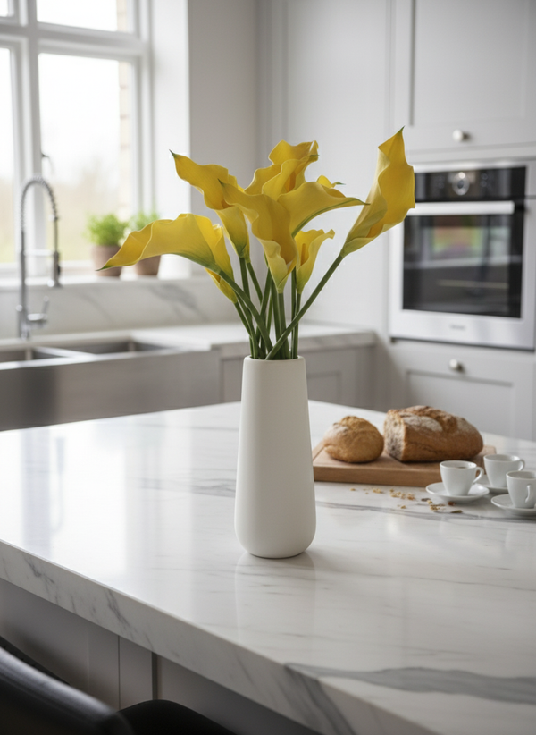 Real touch yellow calla lily arrangement in a minimalist white ceramic vase on a marble kitchen island #yellow