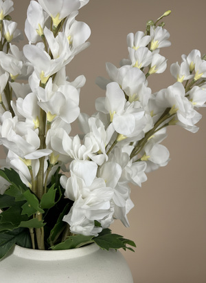 Close-up of real touch faux white delphinium flowers with soft blush petals arranged in a white ceramic vase #white