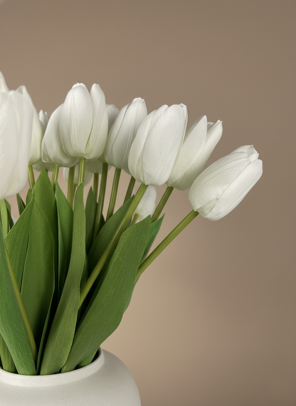 Close up of white faux tulips with realistic petal texture and natural green leaves in a minimalist vase #white
