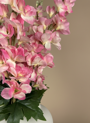 Close-up of real touch faux pink delphinium flowers with soft blush petals arranged in a white ceramic vase #pink