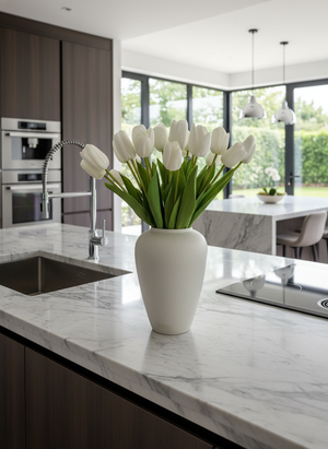 Realistic white faux tulips arranged in a minimalist ceramic vase styled on a modern marble kitchen island #white

