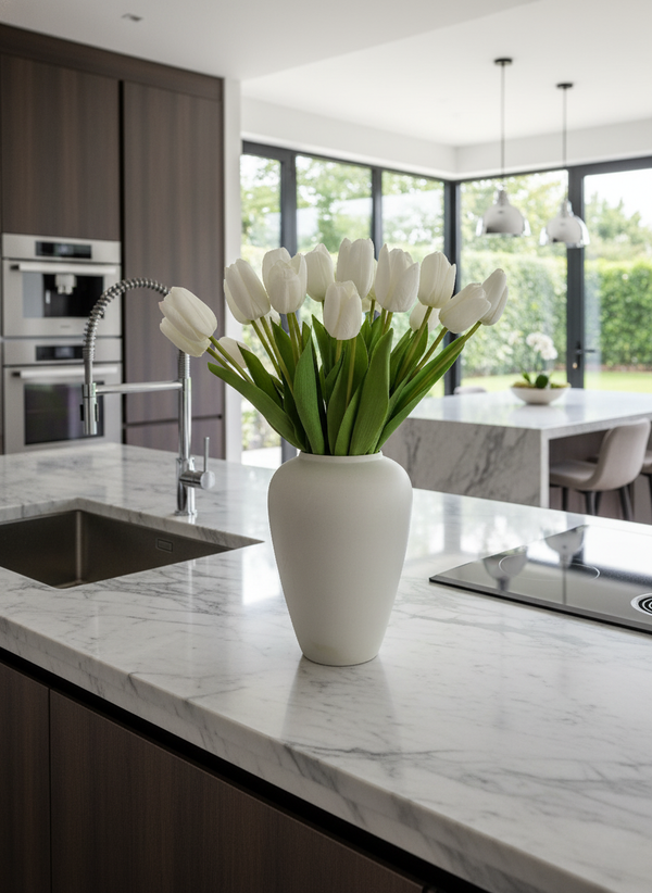 Realistic white faux tulips arranged in a minimalist ceramic vase styled on a modern marble kitchen island #white
