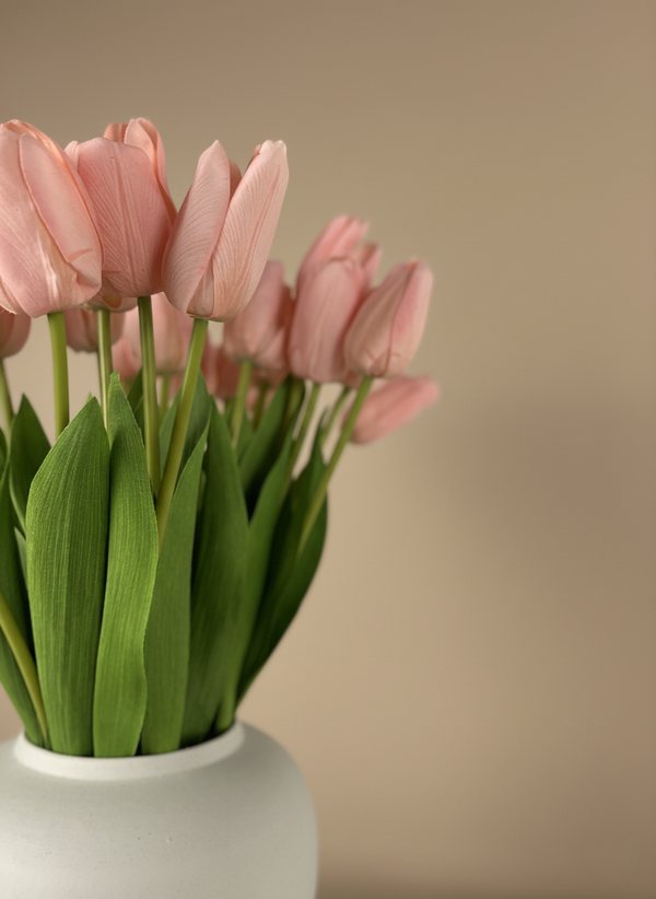 Close up of high-end pink faux tulips with realistic petal texture and natural green leaves in a minimalist vase #baby-pink 