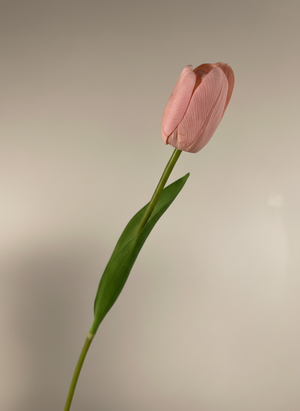 Single real touch pink faux tulip stem with lifelike petals and natural green leaf on beige background #baby-pink