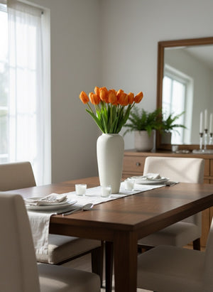 Orange faux tulips arranged in a minimalist ceramic vase on a modern dining table in a light filled interior #apricot-orange
