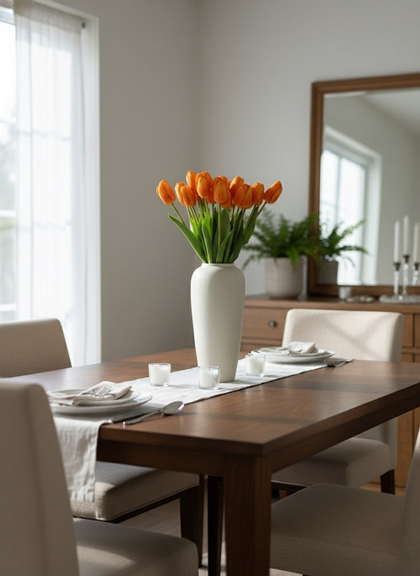 Orange faux tulips arranged in a minimalist ceramic vase on a modern dining table in a light filled interior #apricot-orange
