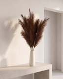 White vase with premium faux brown pampas grass on a concrete surface against a beige background #deep-brown