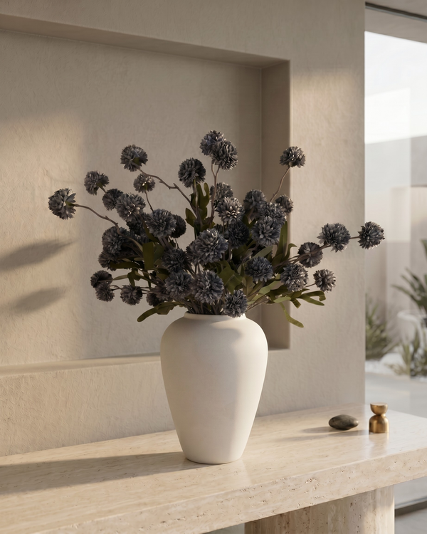 White vase with grey coloured real touch faux pompon flowers on a light wooden surface with a neutral background #grey