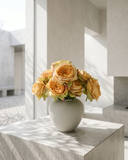Artificial orange rose arrangement with soft layered blooms styled in a matte ceramic vase on a marble surface #apricot-orange