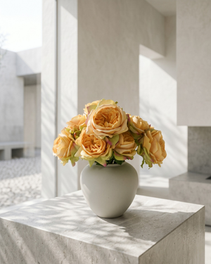 Artificial orange rose arrangement with soft layered blooms styled in a matte ceramic vase on a marble surface #apricot-orange
