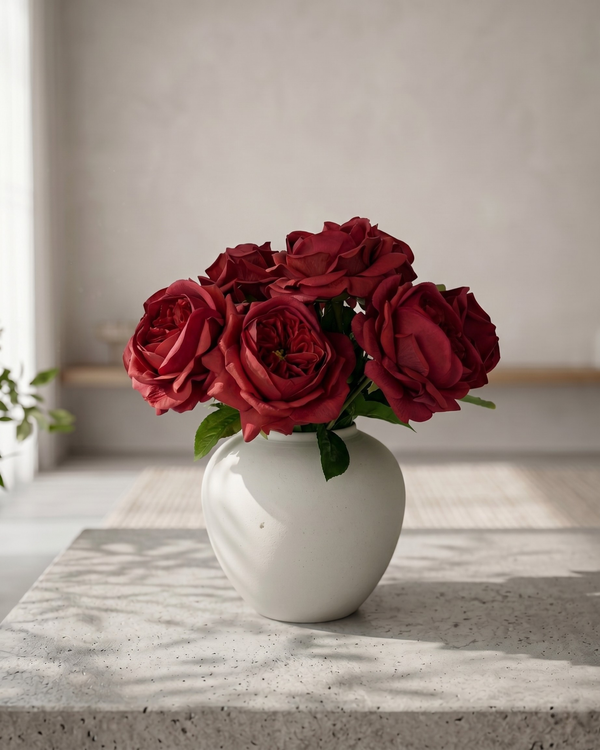 Real touch faux red rose arrangement with soft layered blooms styled in a matte ceramic vase on a concrete surface #red