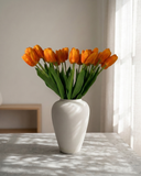 Real touch apricot orange faux tulips in a matte off white ceramic vase styled on a marble table for modern home decor #apricot-orange