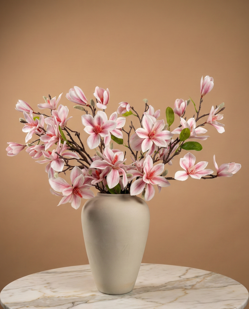 Pink faux magnolia blossom arrangement in large beige vase on marble table, luxury artificial spring floral decor