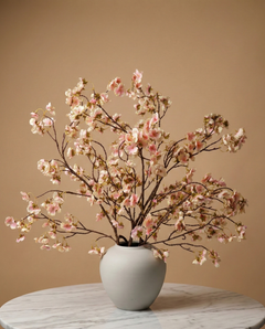 Lifelike faux blush pink cherry blossom branches in a white ceramic vase on a marble table with a tan background #blush-pink