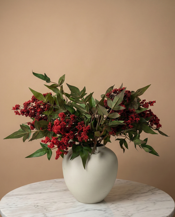 Real touch red faux berry arrangement with green foliage in a minimalist ceramic vase on a marble table #red