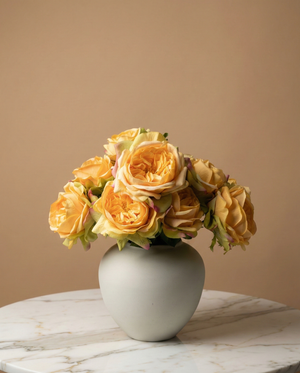 Artificial orange rose arrangement with soft layered blooms styled in a matte ceramic vase on a marble table #apricot-orange