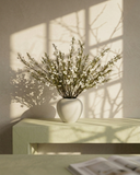 Matte white vase with real touch white faux wax flower arrangement with delicate blooms on a surface with soft shadows #white