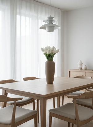 Minimalist dining room with premium white faux tulips in a tan vase on an oak table under a modern pendant light. #white