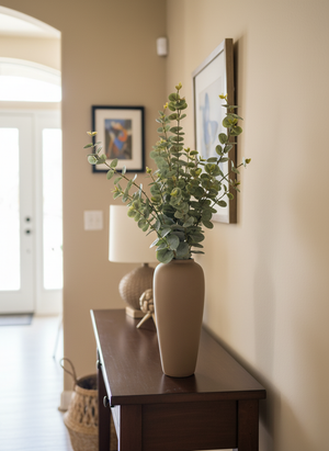 Premium faux eucalyptus arrangement with soft green foliage styled in a matte brown ceramic vase on a hallway console table 