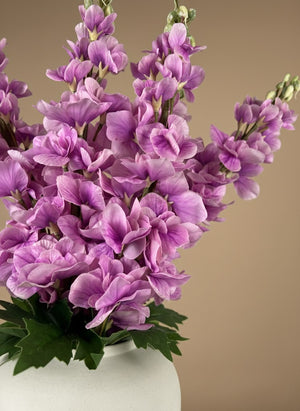 Close-up of real touch faux pink delphinium flowers with soft blush petals arranged in a white ceramic vase #lavender-pink