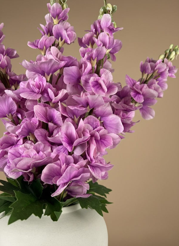 Close-up of real touch faux pink delphinium flowers with soft blush petals arranged in a white ceramic vase #lavender-pink