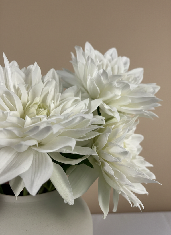 Detailed close-up of artificial white dahlia blooms with layered petals in a ceramic vase #white