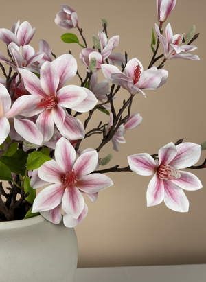 Close-up of realistic pink faux magnolia petals and buds in a ceramic vase, luxury artificial spring floral detail